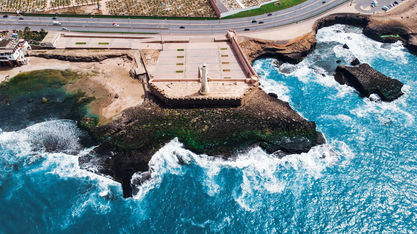 Aerial drone view of Rabat, Morocco. Atlantic ocean rocky coastline with lighthouse, blue water