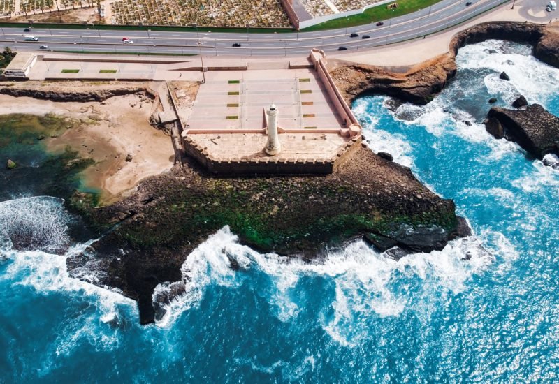 Aerial drone view of Rabat, Morocco. Atlantic ocean rocky coastline with lighthouse, blue water